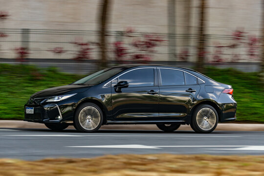 Black Toyota Corolla driving on city street, Popular sedan panning shot, High Resolution