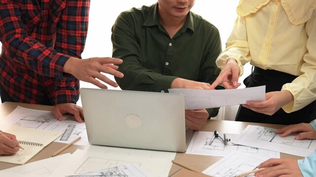 Smart architect and safety engineer discussion about building plan on table with architectural document, measurement tools and wooden block scatter around at modern office. Closeup. Delineation.