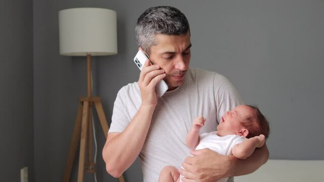 Upset sad young father talking on mobile phone about crying baby boy trying to calm down newborn child rocking kid on his hands asking doctor for advice how to help sick son