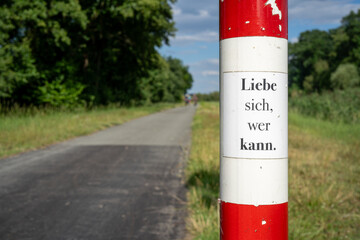 detail of a sign on havel cycle path with text "Liebe sich, wer kann."