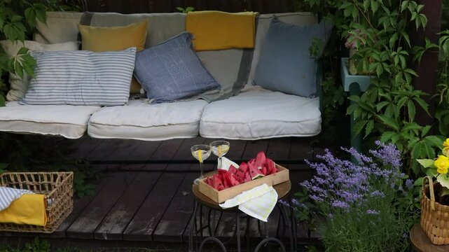 cozy place in the summer garden, garden swing with soft cushions curled with grapes and decorated with flowers in cachepots