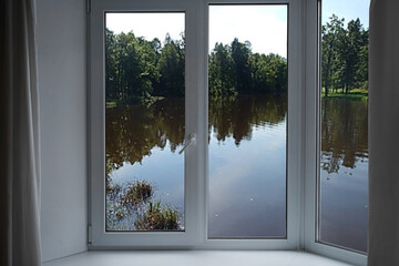 View from the window, green trees, landscape with lake.