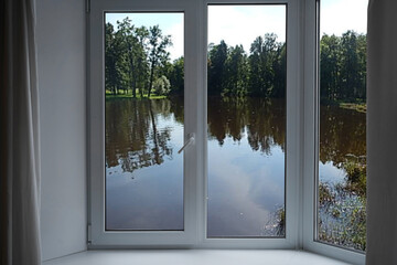 View from the window, green trees, landscape with lake.