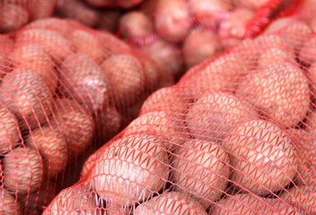 potatoes in net packing at the market. Mesh red bags full of raw potatoes. New harvest. Trade, business