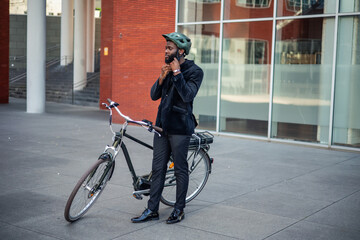 black african american businessman straps on helmet before riding electric bike to work eco-friendly