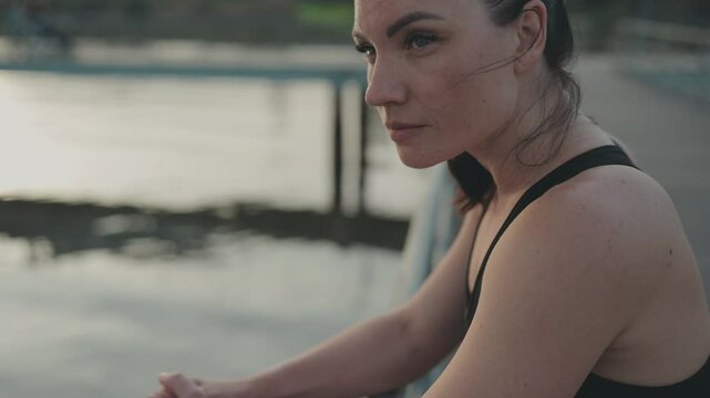 Focused on serenity, a runner woman takes a rest outdoors, enjoying a quiet sunset after a long run.