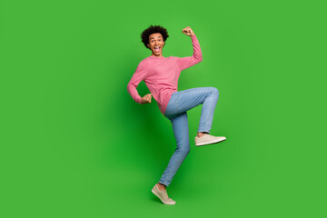 Full length photo of handsome lucky guy wear pink sweater rising fists emtpy space isolated green color background