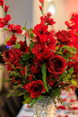 Formal wedding reception with red flowers.