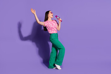 Full body photo of attractive young woman sing microphone karaoke dressed stylish pink clothes isolated on violet color background