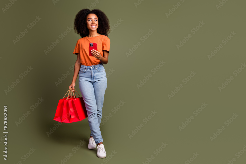 Poster Full length photo of adorable lovely girl wear orange clothes chatting gadget rising shoppers empty space isolated khaki color background