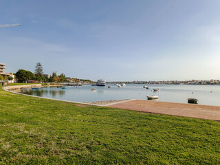 Park with green lawn next to the city bay with boats in river Tejo, Seixal PORTUGAL