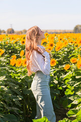 Happy blonde teenage girl in sunflower field.