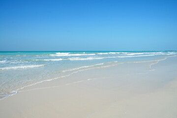 Beautiful soft waves of Blue Ocean with Sandy Beach Background close up. Sea sand wallpaper