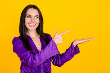 Photo of positive smiling lady promoter hold hand look pointing empty space isolated yellow color background