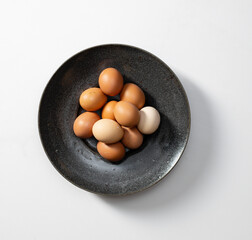 black bowl filled with a variety of brown and white eggs