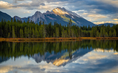 Calm lake reflecting majestic mountain peak at sunset