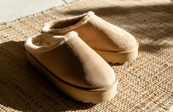 A pair of Uggs slippers on a jute rug.