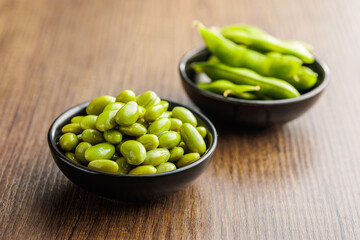Edamame soy beans in bowl on wooden table.