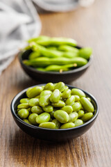 Edamame soy beans in bowl on wooden table.