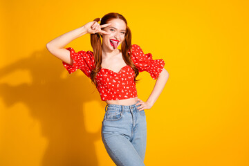 Photo portrait of pretty young girl show v-sign stick tongue out wear trendy red outfit isolated on yellow color background