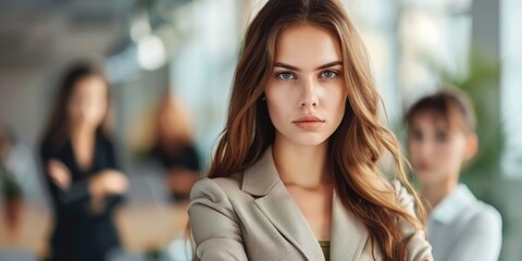 A young woman stands confidently in a modern office setting, her gaze fixed on the camera with a determined expression