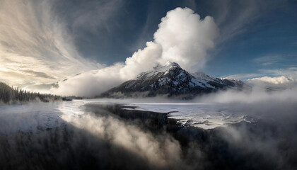 Snow-covered mountain peak with a cloudy sky and shining sun in a dramatic natural landscape shot.