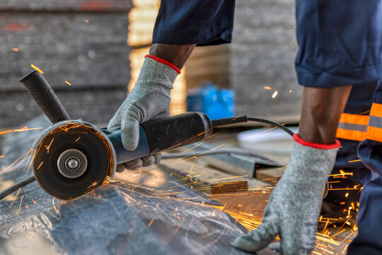 angle grinder, african american worker cutting metal outdoors - Powered by Adobe