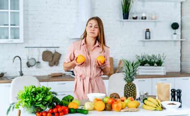 Woman Holding Oranges in Kitchen