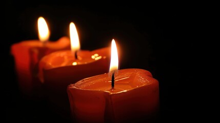 Three red candles burning in the dark