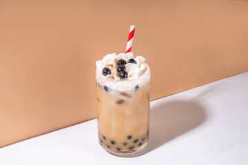 Classic boba bubble tea with tapioca pearls and whipped non-dairy creamer on top of glass, summer...