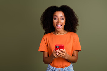 Photo of excited lovely girl wear orange clothes communicating modern gadget empty space isolated khaki color background