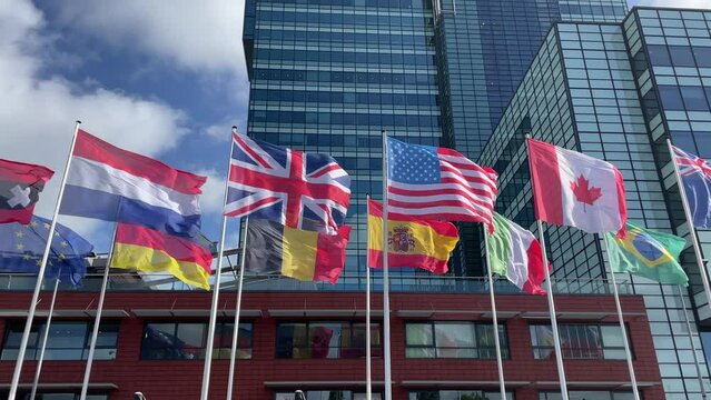 Netherlands, USA, Germany, UK, Span, Canada, Brazil, Belgium, Italy flags flying in the air in front of a office building