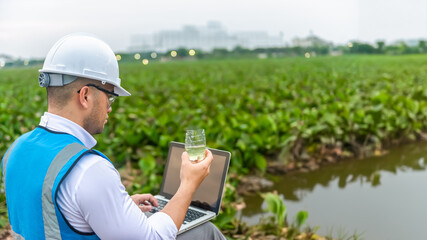 Biologist wastewater treatment sit aside of a lake while looking at the wastewater in a plastic...