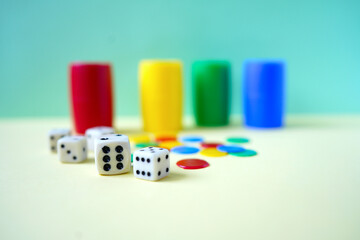 White dices and blur colorful tokens on yellow background .