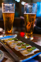 Japanese Beer and Dutch Yellowtail Sashimi with Ponzu Sauce at a Sushi Restaurant High Top Bar Table