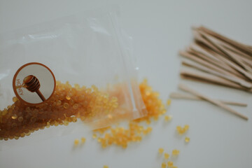  pack of yellow depilatory wax balls and wooden stirring sticks