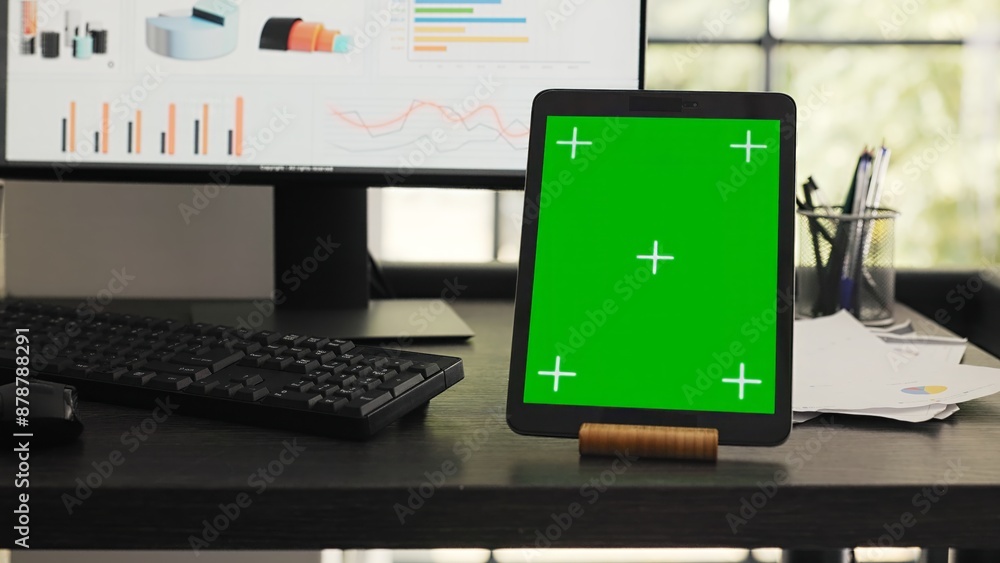Poster desk with greenscreen on modern tablet in business coworking space, showing isolated chromakey layou
