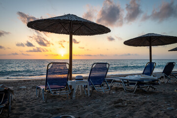 Sunset on a holiday beach with sunbeds and umbrellas.