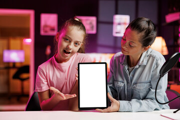 Small girl and mom using professional recording gear to film video assessing mockup tablet performance. Daughter and parent shoot isolated screen digital device review for online channel