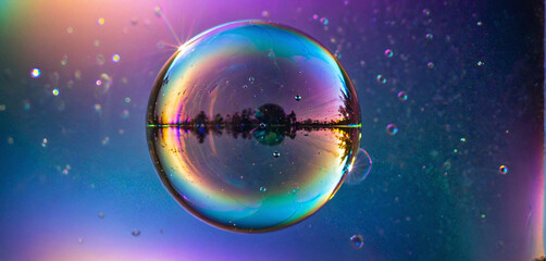 The refraction and interference of light on the thin surface layer of a soap bubble causes it to shine very colorful