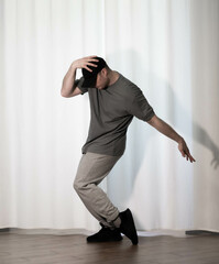 Dance in motion, pose of a man in hip-hop style clothes. Sports dancing guy in training poses. Dance training at home.