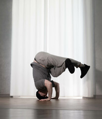 Dance in motion, pose of a man in hip-hop style clothes. Sports dancing guy in training poses. Dance training at home.