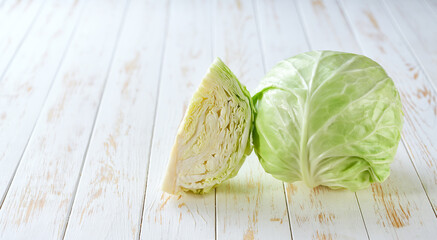 Whole and quarter fresh green cabbage on a light table, copy space for text.