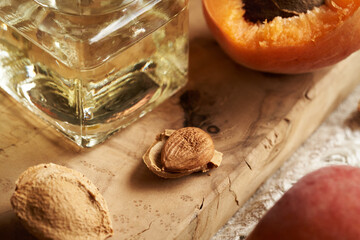 Closeup of a raw apricot seed with a bottle of apricot kernel oil on a table