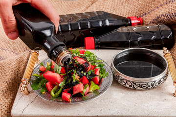 Pomegranate syrup and salad. A girl pouring pomegranate syrup on seasonal salad.