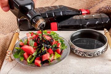 Pomegranate syrup and salad. A girl pouring pomegranate syrup on seasonal salad.