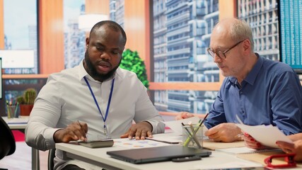 Senior woman reads the new retirement plan contract in a meeting with broker, agreeing to agency terms and securing their pension for the future. Life insurance financial options. Camera A.