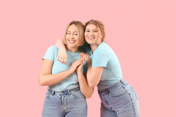 Beautiful happy women in stylish jeans on pink background