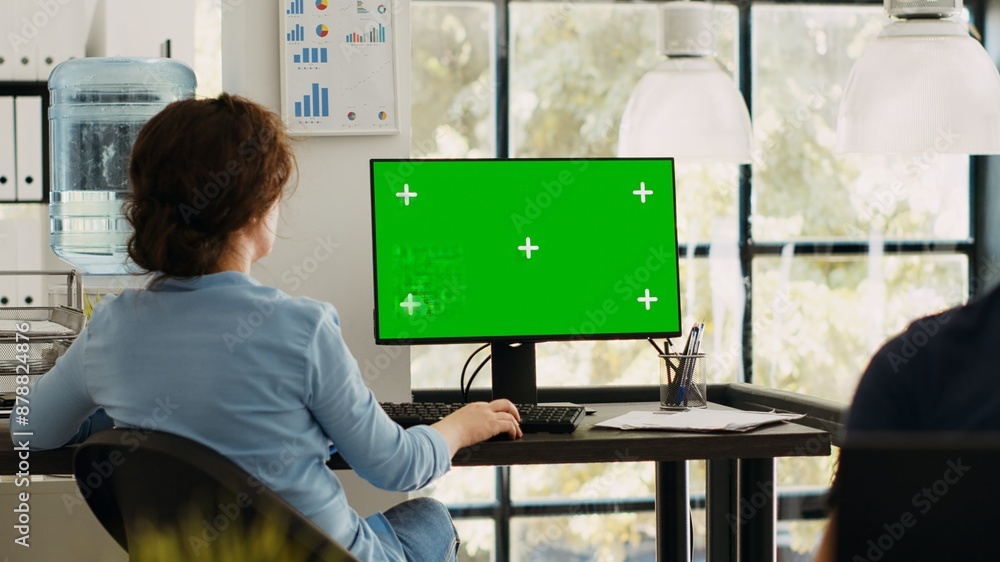 Poster business manager working at monitor showing blank greenscreen template, sitting at office workstatio