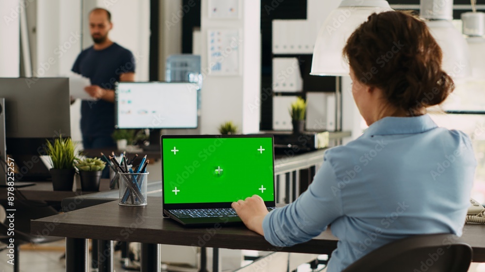 Poster specialist using laptop with greenscreen to solve business tasks and operations in office, looking a